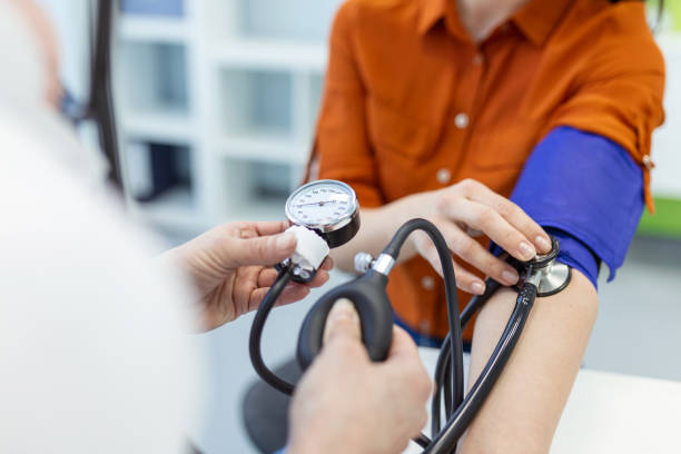 청진기로 스피그마노미터를 사용하는 의사가 병원의 환자에게 혈압을 검사합니다. - 고혈압 뉴스 사진 이미지