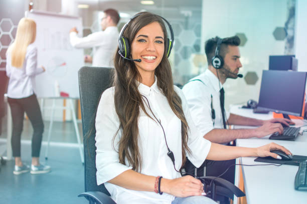 istock Young positive woman customer support phone operator in microphone headset working on computer in the office 1373090033