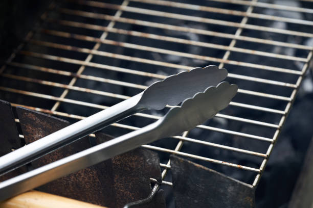 Stainless steel grill tongs on a dirty grill rust. Wooden handle blurred in the foreground. Stainless steel grill tongs on a dirty grill rust. Wooden handle blurred in the foreground. serving tongs stock pictures, royalty-free photos & images