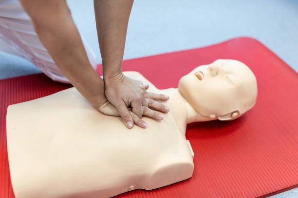 istock CPR training medical procedure - Demonstrating chest compressions on CPR doll in the class. First Aid Training - Cardiopulmonary resuscitation. First aid course on cpr dummy. 1373091936