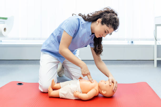 mujer realizando rcp en muñeca de entrenamiento de bebé con compresión de una mano. entrenamiento en primeros auxilios - reanimación cardiopulmonar. curso de primeros auxilios sobre dummy de rcp. - cpr first aid paramedic rescue fotografías e imágenes de stock