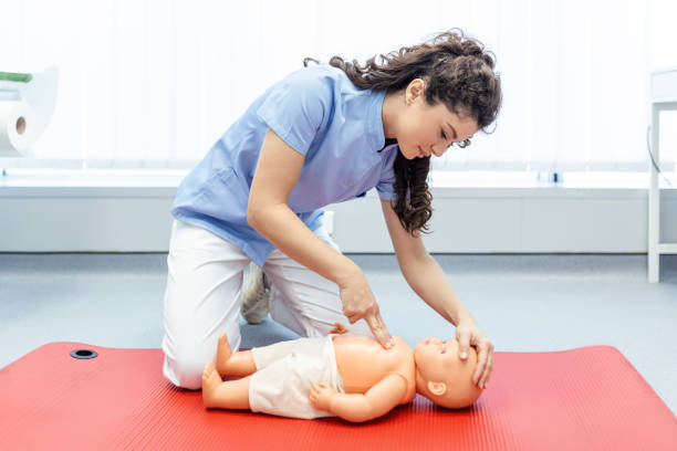 Woman performing CPR on baby training doll with one hand compression. First Aid Training - Cardiopulmonary resuscitation. First aid course on cpr dummy. Woman performing CPR on baby training doll with one hand compression. First Aid Training - Cardiopulmonary resuscitation. First aid course on cpr dummy. first aid class stock pictures, royalty-free photos & images