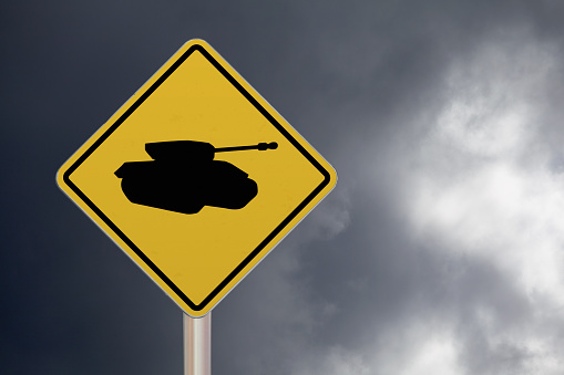 Diamond-shaped crossing sign with yellow background and black border with a tank in the middle.