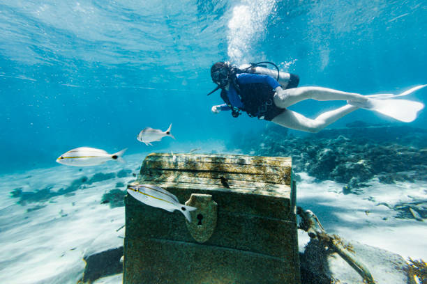 teenage girl scuba diving over a pirate chest on the bottom of the sea - antiquities imagens e fotografias de stock