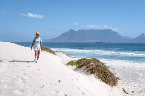Bloubergstrand Cape Town South Africa on a bright summer day, Blouberg beach, withe powder sand and blue ocean. woman wiht hat walking at the beach