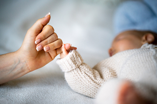 Close-up of mother's hand holding newborn baby's hand
