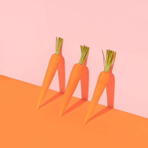istock Spring creative layout with carrots leaning against bright orange and pastel pink background. 80s, 90s retro romantic aesthetic spring or Easter concept. Minimal vegetable fashion idea. 1373099355