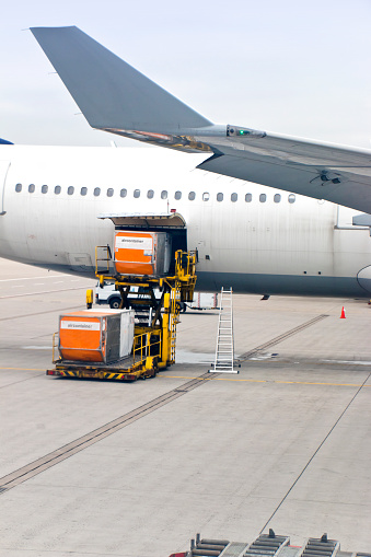 Freight containers are loaded into an aircraft on an airport apron. This image is part of an airport series.