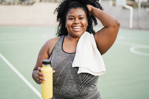 istock Curvy african woman smiling at camera while doing running routine in park city - Focus on face 1373099539