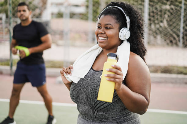 Curvy woman doing workout morning routine outdoor at city park - Focus on face stock photo