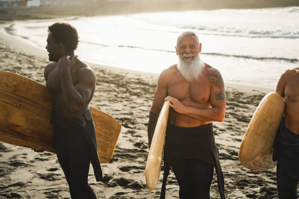 istock Multi generational surfer friends having fun on the beach after surf session - Focus on senior man face 1373099622