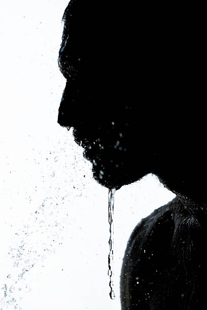 Water frozen in time dripping of a silhouetted mans face and body.