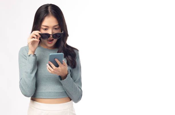 istock Surprise asian young woman using mobile phone standing on white background and copy space Young girl using smartphone for shopping online chatting texting message Beauty lady get shock and surprise 1373110650