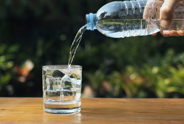 istock Pour water into a glass on wooden table in nature background. 1373111065
