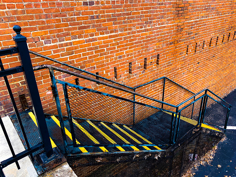 a city industrial fire escape emergency exit stairway metal iron caution brick alley safety building staircase