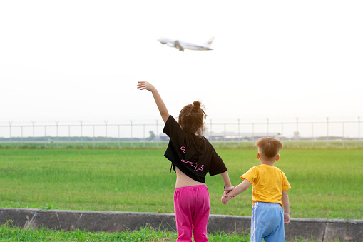 Children watch planes take off and land next to the airport on weekends.