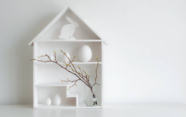 istock Home minimalist interior with Easter decor. Branches with budding buds in a glass vase on shelves in the shape of a house, 1373117001