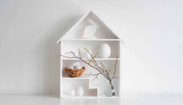 istock Home minimalist interior with Easter decor. Branches with budding buds in a glass vase on shelves in the shape of a house, 1373117008