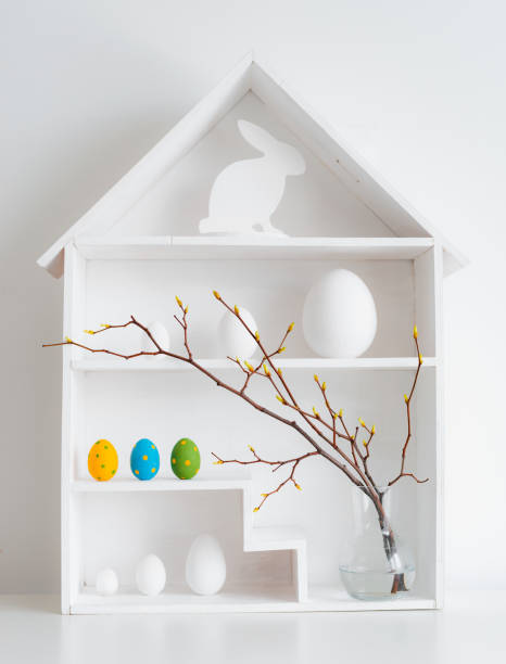 istock Home minimalist interior with Easter decor. Branches with budding buds in a glass vase on shelves in the shape of a house, 1373117021