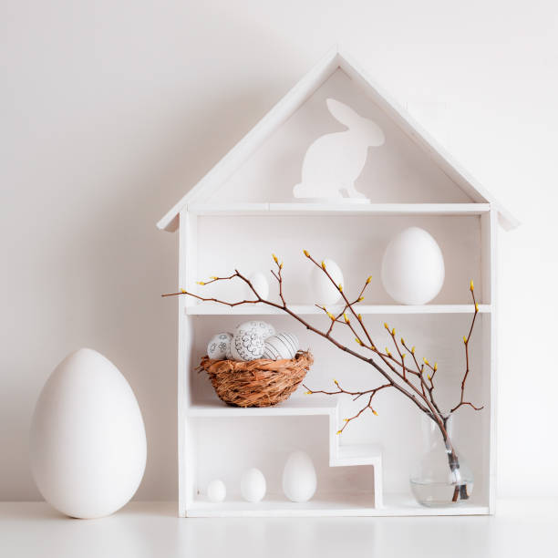 istock Home minimalist interior with Easter decor. Branches with budding buds in a glass vase on shelves in the shape of a house, 1373117024