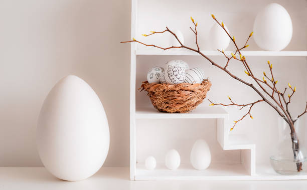 istock Home minimalist interior with Easter decor. Branches with budding buds in a glass vase on shelves in the shape of a house, 1373117027