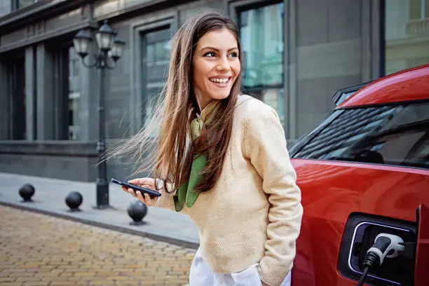 Portrait of woman charging her electric car