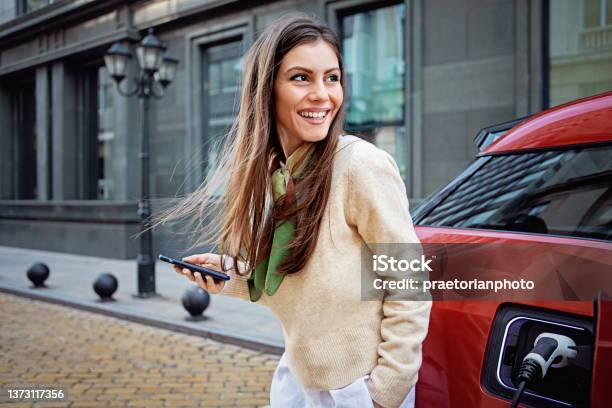 Portrait Of Woman Charging Her Electric Car Stok Fotoğraflar & Araba - Motorlu Taşıt‘nin Daha Fazla Resimleri - Araba - Motorlu Taşıt, Elektrikli Araba, Kadın