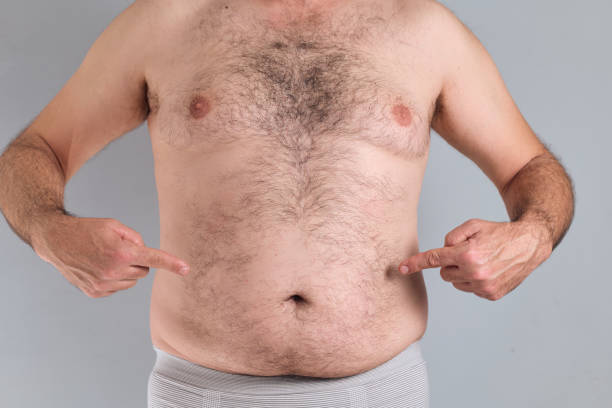 Caucasian man pointing at his nude fat hairy belly, isolated on grey background, nude image Caucasian man pointing at his nude fat hairy belly, isolated on gray background hairy fat man pictures stock pictures, royalty-free photos & images