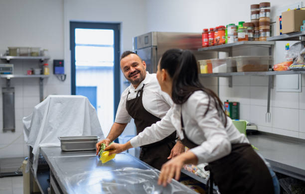 istock Chef and cook cleaning the workspace after doing dishes indoors in restaurant kitchen. 1373121316