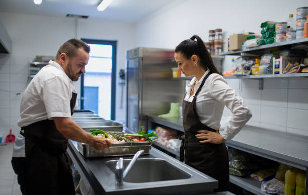 istock Cook washing vegetables in sink in commercial kitchen. 1373121379