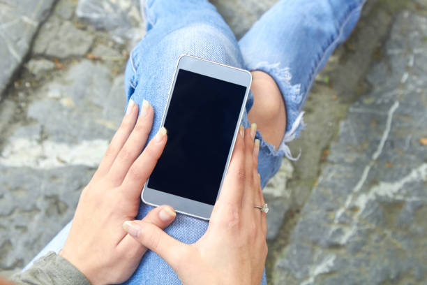 istock Woman in jeans using modern smartphone outdoors. 1373124658