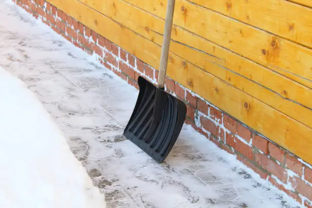 Snow shovel. Removing snow from a path in the yard. Clean. Close-up. Selective focus. Background. Texture.