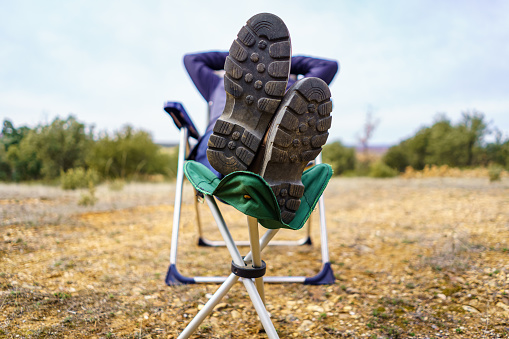 Man sitting in a camping chair with his feet up on a footrest.