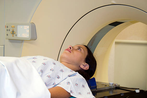 Young Woman on CAT Scan Table Young Woman on CAT Scan Table pet scan photos stock pictures, royalty-free photos & images