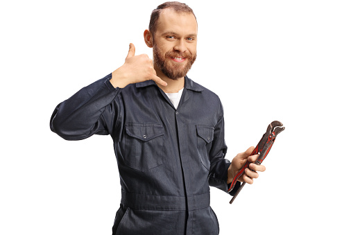 Plumber in a uniform holding pliers and gesturing call me sign isolated on white background