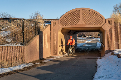 senior male cyclist is riding through railroad underpass on a biking trail in Fort Collins, Colorado in winter scenery