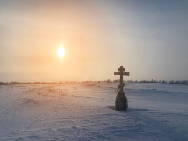 Christian cross in winter. Holy place or lonely grave in winter field