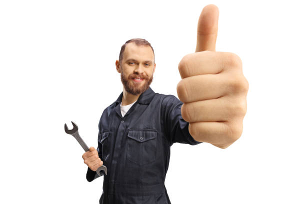mecánico posando con una llave inglesa en la mano y gesticulando pulgares hacia arriba - manual worker thumbs up hand sign adult fotografías e imágenes de stock