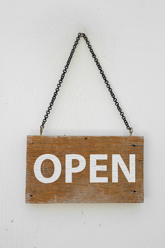 Open sign on wooden planks hanging on the white wall.