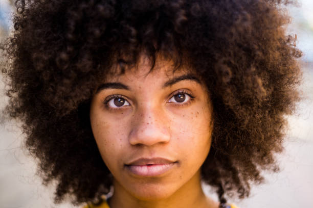 porträt und nahaufnahme einer schönen jungen afrikanischen oder amerikanischen frau, die in die kamera schaut - women african descent serious human face stock-fotos und bilder