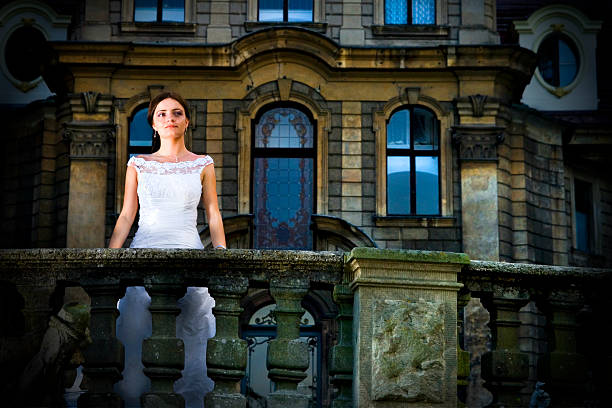 Young classy woman standing on palace terrace by a stone railing.