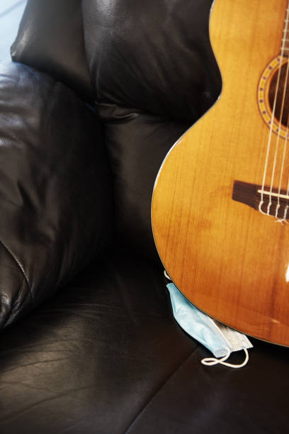 istock Surgical mask with a beautiful classical guitar on a leather sofa 1373135865
