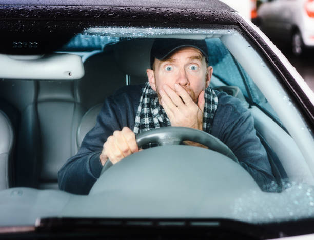 gefahr voraus: fahrer mit großen augen bekommt einen schrecklichen schreck, als er sein auto fährt - fear terrified shock humor stock-fotos und bilder