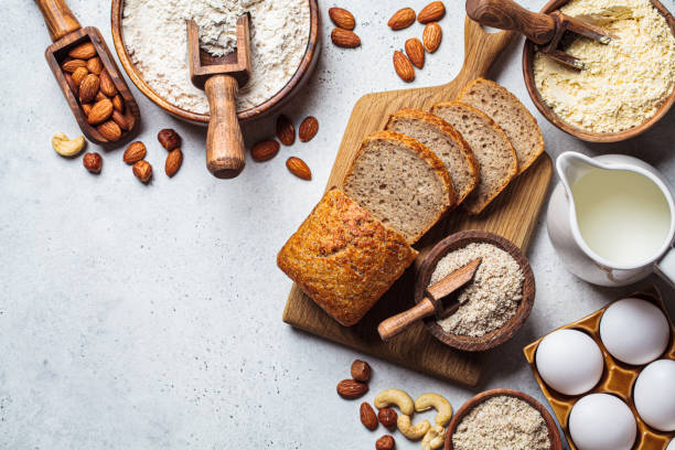 cottura del pane keto. diversi tipi di farina di noci - mandorle, nocciole, anacardi e ingredienti da forno, sfondo scuro. - bread foto e immagini stock