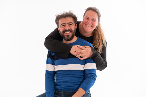 Studio shot of happy couple standing together at isolated white background. Women hugging his partner.