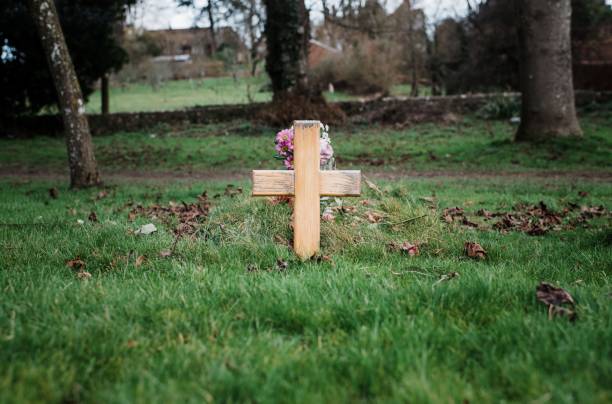 istock wooden cross at a graveyard cemetary with flowers 1373137231