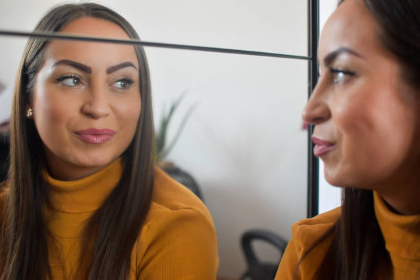 istock Woman indoors looking herself in mirror 1373140130