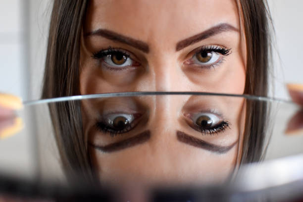 frau drinnen hält einen spiegel vor ihren augen - seeing double stock-fotos und bilder