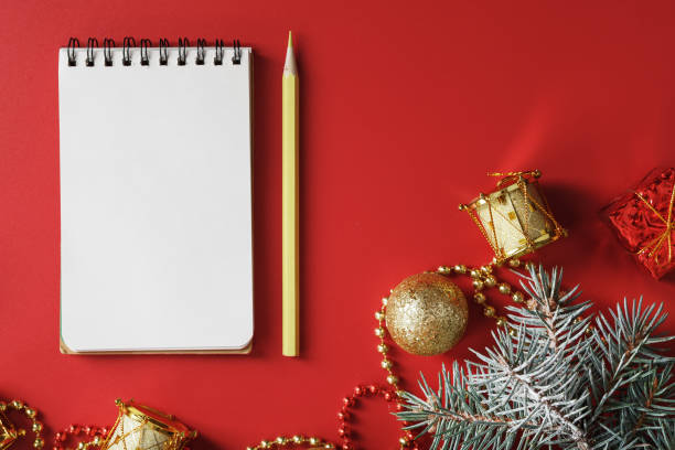 istock Christmas composition with notepad and a pencil for writing wishes with Christmas tree decorations on a red background. 1373142071