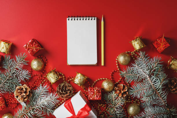 istock Christmas composition with notepad and a pencil for writing wishes with Christmas tree decorations on a red background. 1373142175